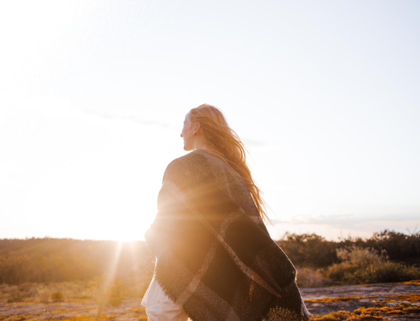 a woman walks towards a sunrise indicating individual addiction treatment therapy and movement