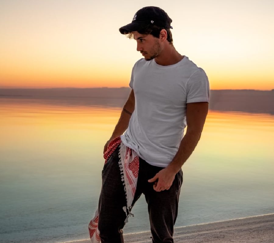 Man pondering while walking on a tranquil lake beach, symbolizing the contemplative journey of synthetic drug rehab in Arkansas.