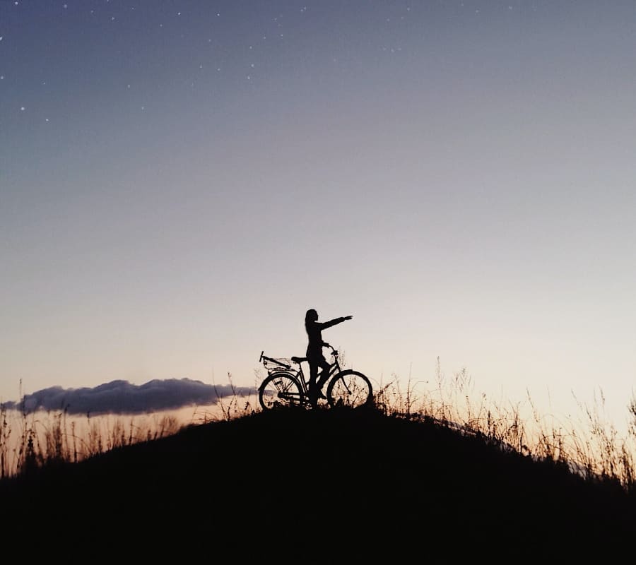 Person on a bicycle at night pointing towards a distant goal, symbolizing the journey towards stabilization in addiction treatment.