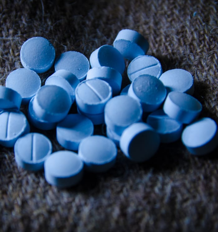 Blue pills on a counter, representing the benzodiazepines that our Benzo Rehab program is designed to help individuals overcome.