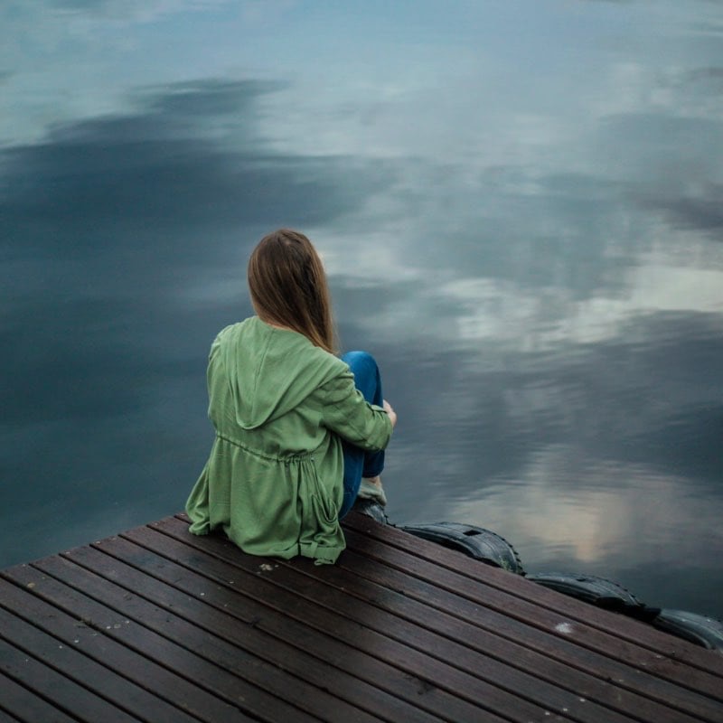 Woman gazing at a tranquil lake, symbolizing hope and peaceful reflection during the journey at the EagleCrest heroin rehab