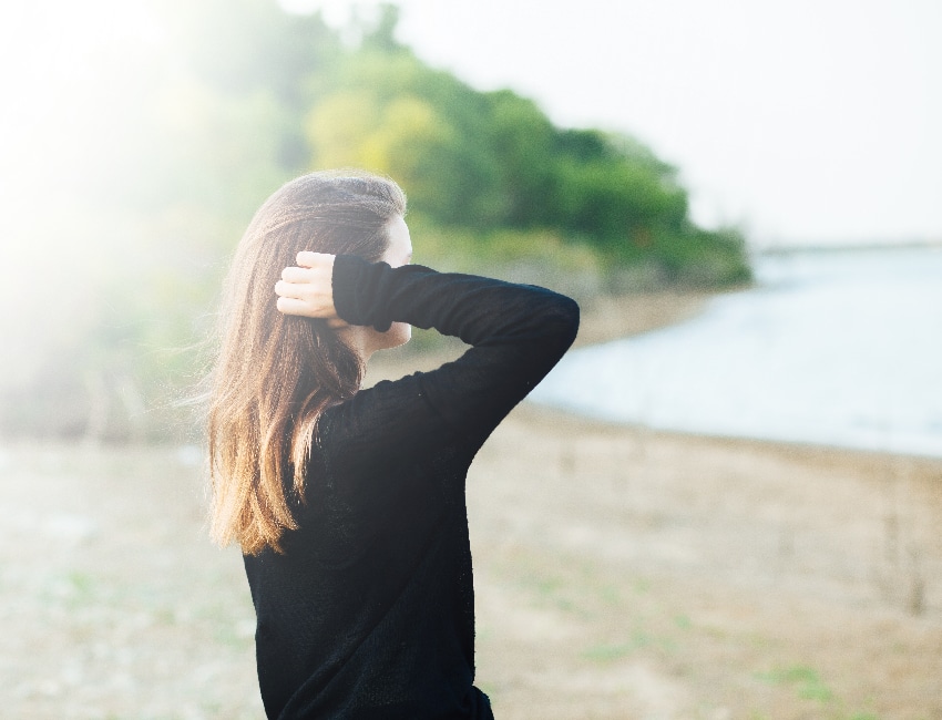 Woman gazing at a serene lake, embodying the inner peace fostered through our Holistic Addiction Treatment in Arkansas.