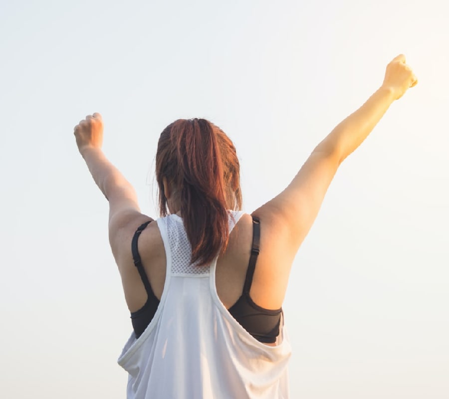 Woman with arms raised in triumph, celebrating her progress in the residential addiction treatment program in Benton County, Arkansas.