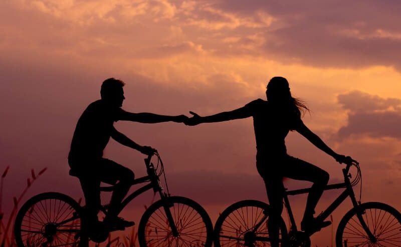 Two individuals riding bikes side by side, holding hands, symbolizing unity family support for meth addict.
