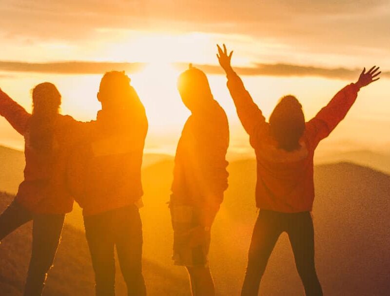 Group celebrating recovery during a sunset, showcasing the unity experienced in types of group therapy.