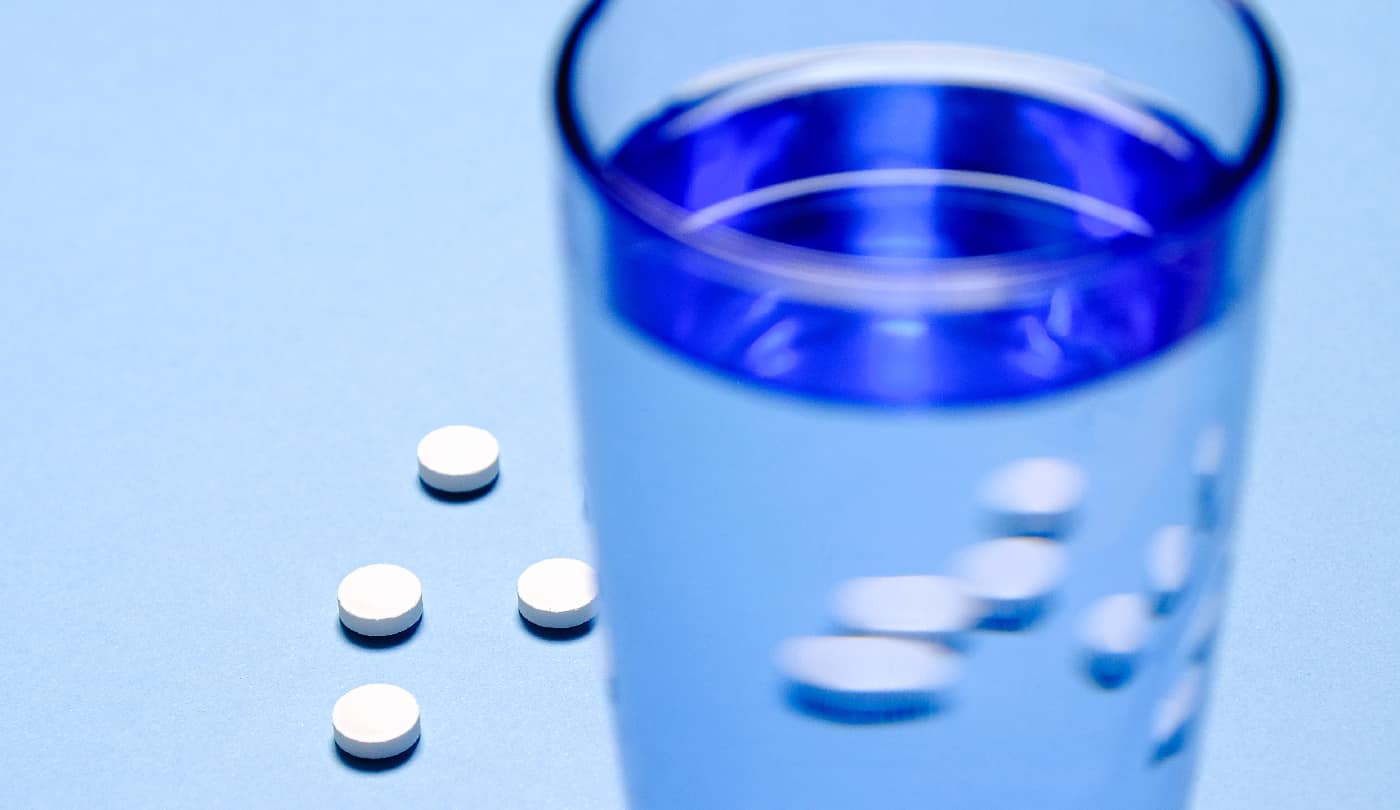 1. Glass of water in sharp focus with blurred pills in the background, highlighting the subtle dangers of Librium addiction.