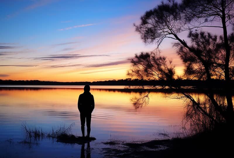 Individual reflecting by a serene lake at sunrise, symbolizing hope beyond the struggles of 'Shake and Bake Meth' addiction.