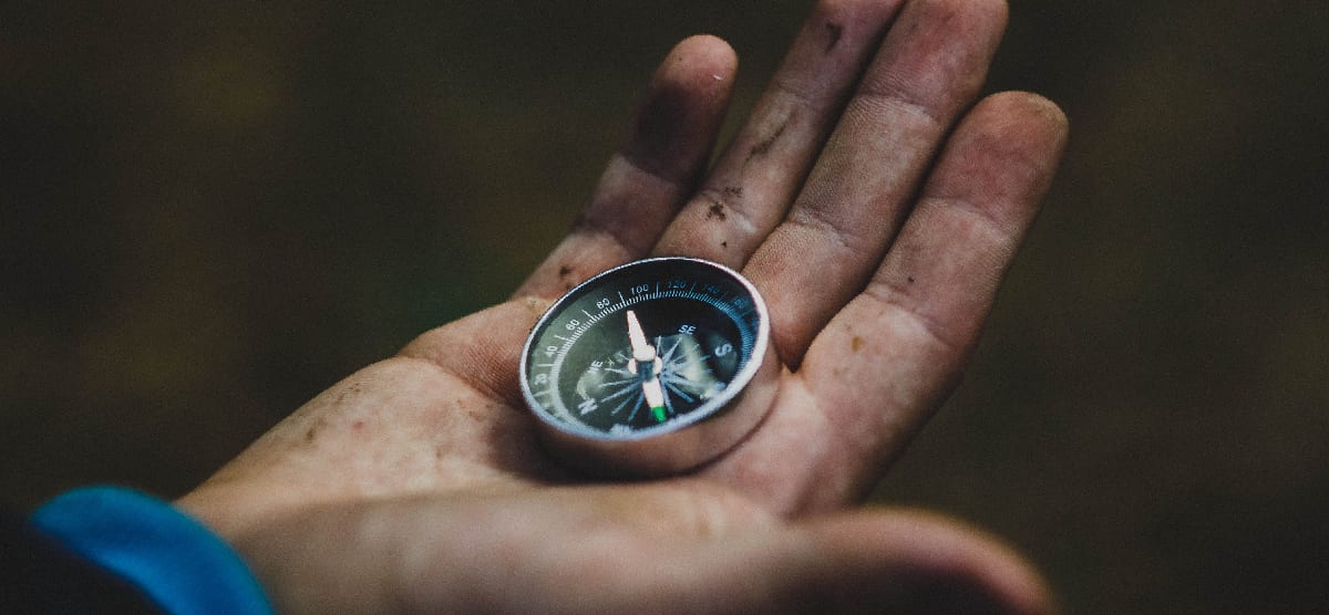 A hand holding a compass, symbolizing the guidance and direction provided by addiction treatment centers in navigating the challenging terrain of drug relapse.