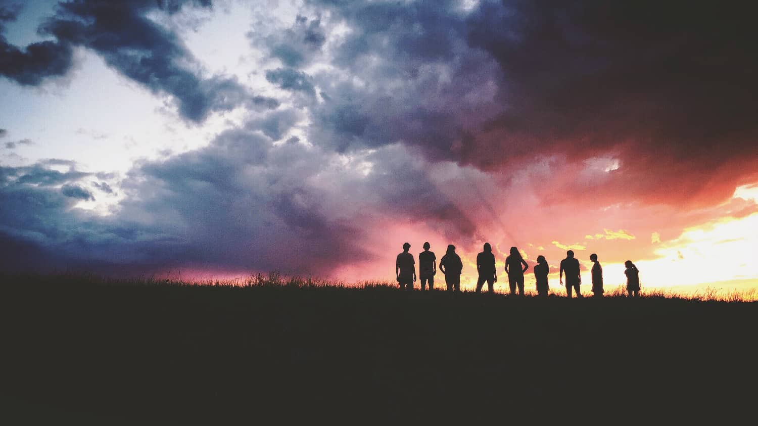 Silhouette of people in a field at sunset, conveying unity and hope in the context of addiction treatment covered by Blue Cross Blue Shield Arkansas.