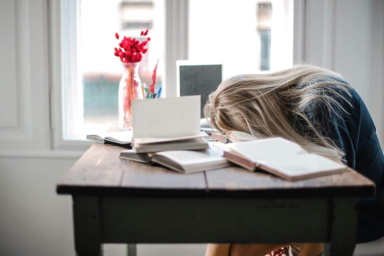 Woman sleeping at her desk with books open showing how benzodiazepine examples can inhibit your daily life.