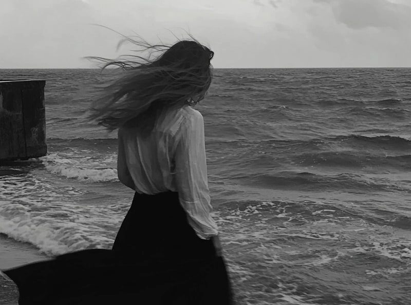 Moody, black and white image of a woman in the wind watching the sea as a symbol of barbiturate abuse