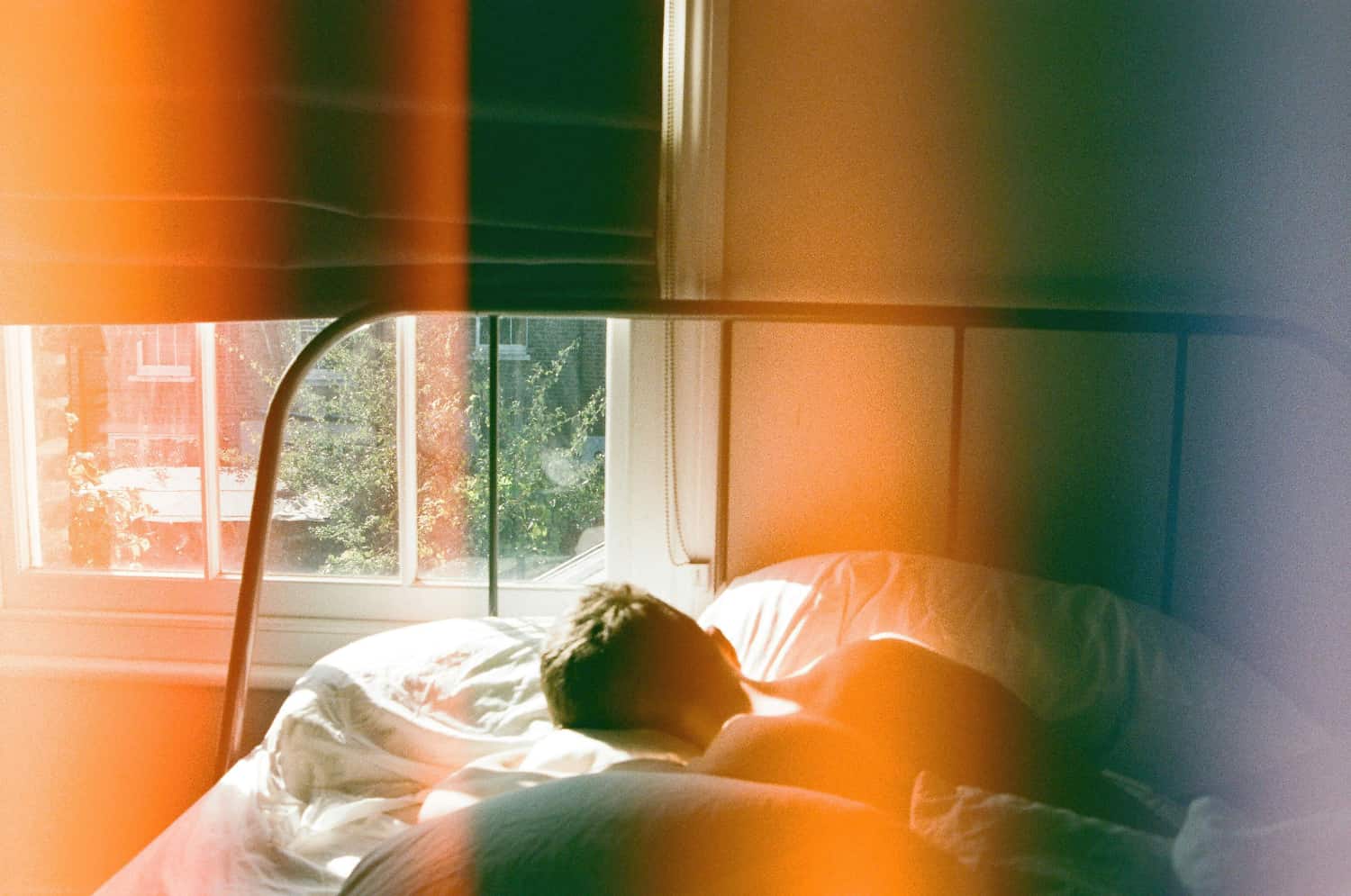 Man sleeps in a room with film effects and light leak showing the dangers of sleeping pill overdose