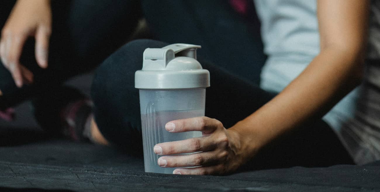 Woman holds a water bottle showing that hydrating can help with how drinking alcohol affects your skin.