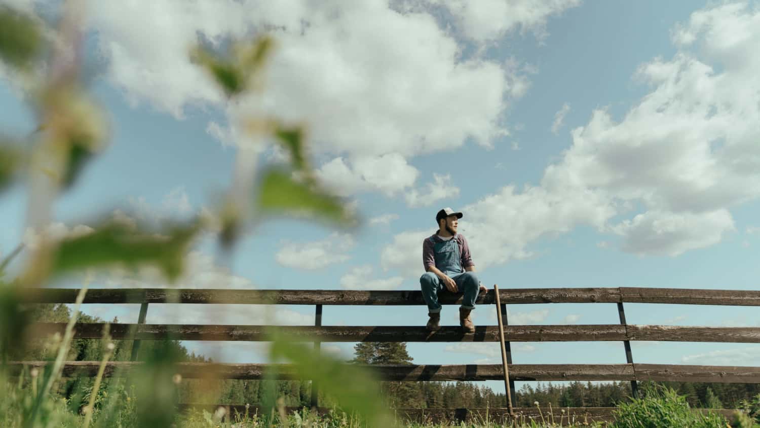 Man sits on a fence on a farm thinking about going to rehab in rural areas.