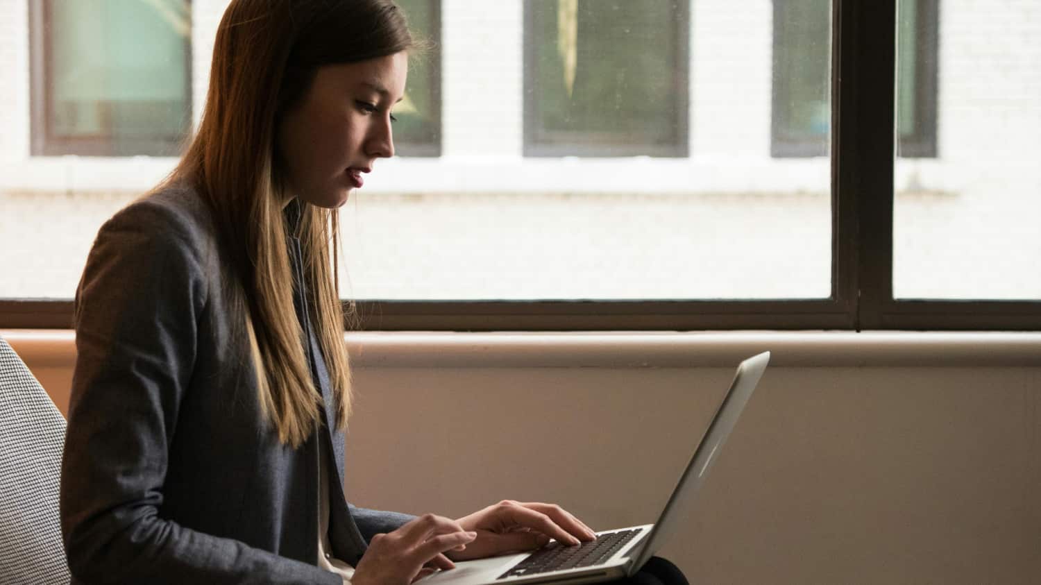 Woman in a school room works on her computer looking for AI help with addiction recovery.