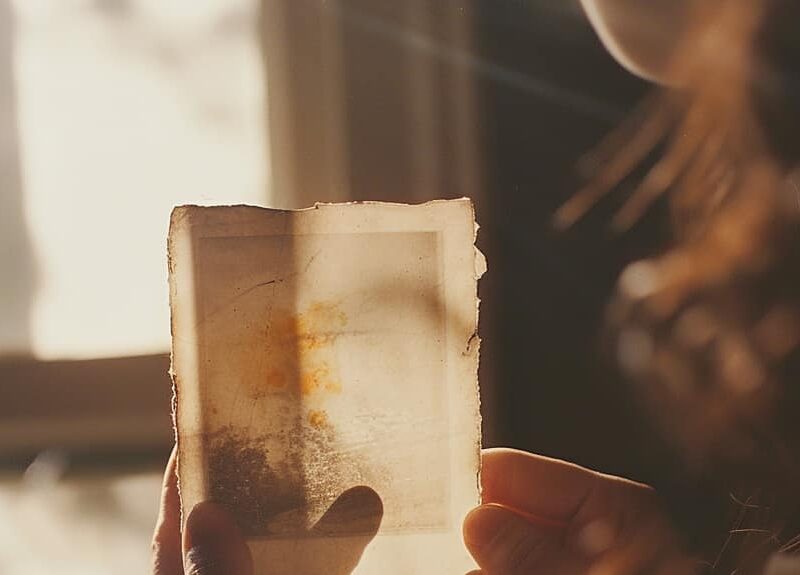 Woman looks at a faded polaroid photograph to show the effects of drug-induced amnesia.