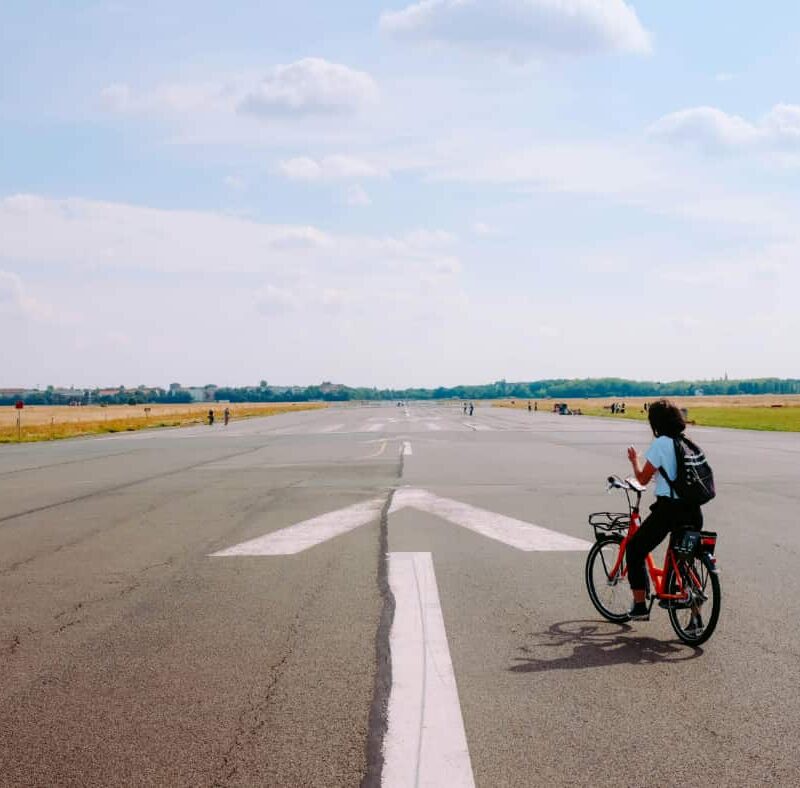 Man on a bicycle on a runway next to a large arrow, showing that if you start short-term addiction rehab, you are going the right way.